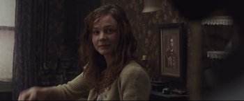 Movie still from “Suffragette” (2015), directed by Sarah Gavron – A young woman sitting in front of a painting in a living room; Medium shot, Over the shoulder angle