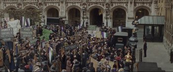Movie still from “Suffragette” (2015), directed by Sarah Gavron – A large crowd of people are gathered in front of a building; Extreme Wide shot, High angle