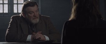 Movie still from “Suffragette” (2015), directed by Sarah Gavron – An older man sitting in front of a woman in a suit; Medium shot, Over the shoulder angle