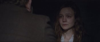 Movie still from “Suffragette” (2015), directed by Sarah Gavron – A young woman stares into the camera with a dark background; Close Up shot, Over the shoulder angle
