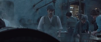 Movie still from “Suffragette” (2015), directed by Sarah Gavron – A man wearing a hat standing next to a woman; Medium shot, Over the shoulder angle