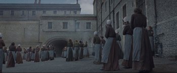 Movie still from “Suffragette” (2015), directed by Sarah Gavron – A group of people standing in front of a brick building; Extreme Wide shot, High angle