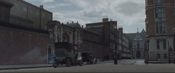 Movie still from “Suffragette” (2015), directed by Sarah Gavron – An old car is parked on the side of the road; Extreme Wide shot, Low angle