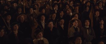Movie still from “Suffragette” (2015), directed by Sarah Gavron – A group of people in a crowd wearing hats; Medium shot, High angle