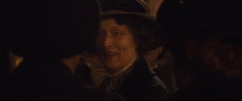 Movie still from “Suffragette” (2015), directed by Sarah Gavron – An older woman wearing a hat and smiling for the camera; Close Up shot, Over the shoulder angle