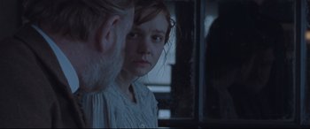 Movie still from “Suffragette” (2015), directed by Sarah Gavron – A young woman looking into a mirror while standing next to an older man; Close Up shot, Over the shoulder angle