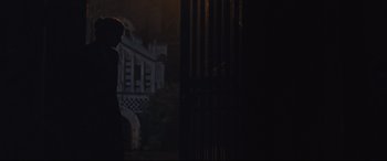 Movie still from “Suffragette” (2015), directed by Sarah Gavron – A man standing in front of a building in the dark; Extreme Wide shot, Over the shoulder angle