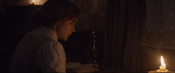 Movie still from “Suffragette” (2015), directed by Sarah Gavron – A young girl sitting in front of a candle; Medium shot, Over the shoulder angle