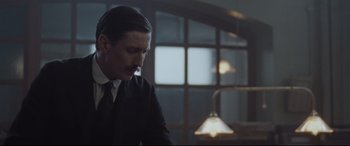 Movie still from “Suffragette” (2015), directed by Sarah Gavron – A man wearing a suit and tie standing in front of a window; Medium shot, Low angle