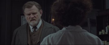 Movie still from “Suffragette” (2015), directed by Sarah Gavron – An older man in a suit looking in the mirror; Medium shot, Over the shoulder angle