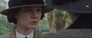 Movie still from “Suffragette” (2015), directed by Sarah Gavron – A young woman wearing a hat looking at the camera; Close Up shot, Over the shoulder angle