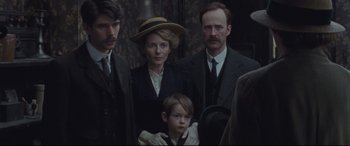 Movie still from “Suffragette” (2015), directed by Sarah Gavron – A group of people standing next to each other in a room; Medium shot, Over the shoulder angle