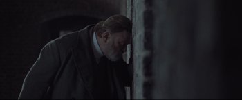 Movie still from “Suffragette” (2015), directed by Sarah Gavron – A man leaning against a wall with his head on his hand; Close Up shot, Over the shoulder angle