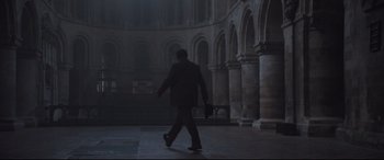 Movie still from “Suffragette” (2015), directed by Sarah Gavron – A man in a suit walking in a dark room; Wide shot, Low angle