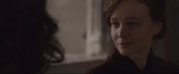 Movie still from “Suffragette” (2015), directed by Sarah Gavron – A young woman looking at the camera in a dark room; Close Up shot, Over the shoulder angle