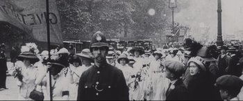 Movie still from “Suffragette” (2015), directed by Sarah Gavron – A black and white photo of a crowd of people; Medium shot, Low angle