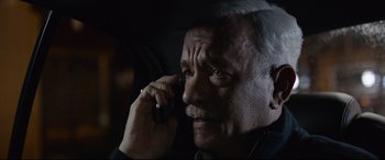 Movie still from “Sully” (2016), directed by Clint Eastwood – An older man talking on a cell phone in a car; Close Up shot, High angle
