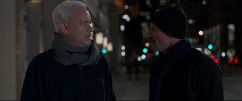 Movie still from “Sully” (2016), directed by Clint Eastwood – Two older men standing next to each other on the sidewalk; Medium shot, Over the shoulder angle