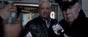 Movie still from “Sully” (2016), directed by Clint Eastwood – A man in a black leather jacket is being interviewed; Close Up shot, Over the shoulder angle