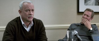 Movie still from “Sully” (2016), directed by Clint Eastwood – An older man sitting in front of another man holding a glass; Close Up shot, Over the shoulder angle