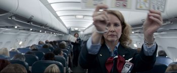 Movie still from “Sully” (2016), directed by Clint Eastwood – A flight attendant is holding a pair of handcuffs on a plane; Medium shot, Low angle