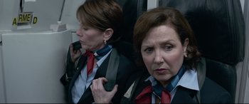 Movie still from “Sully” (2016), directed by Clint Eastwood – Two women in suits and ties on a train; Medium shot, Over the shoulder angle