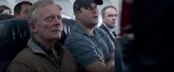 Movie still from “Sully” (2016), directed by Clint Eastwood – A group of men sitting next to each other on a plane; Medium shot, Over the shoulder angle