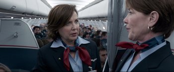 Movie still from “Sully” (2016), directed by Clint Eastwood – A woman in a flight attendant's uniform on an airplane; Close Up shot, Over the shoulder angle