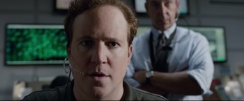 Movie still from “Sully” (2016), directed by Clint Eastwood – A man wearing a headset with another man sitting in the background; Close Up shot, Over the shoulder angle