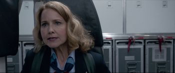 Movie still from “Sully” (2016), directed by Clint Eastwood – A woman sitting in a chair with a backpack; Close Up shot, Low angle