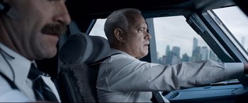 Movie still from “Sully” (2016), directed by Clint Eastwood – An older man sitting in the driver's seat of a car; Close Up shot, Over the shoulder angle