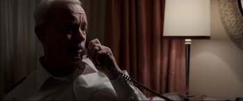 Movie still from “Sully” (2016), directed by Clint Eastwood – An older man talking on a phone while sitting in a chair; Close Up shot, High angle