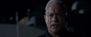 Movie still from “Sully” (2016), directed by Clint Eastwood – An older man with a white beard is looking at the camera; Close Up shot, Over the shoulder angle