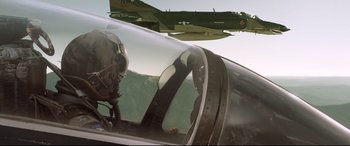 Movie still from “Sully” (2016), directed by Clint Eastwood – A fighter jet flying in the sky next to a pilot's helmet; Medium shot, Low angle
