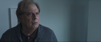 Movie still from “Sully” (2016), directed by Clint Eastwood – An older man wearing a gray jacket looking at the camera; Close Up shot, Over the shoulder angle