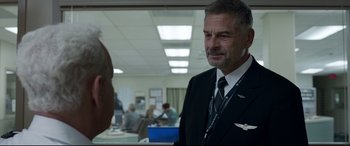 Movie still from “Sully” (2016), directed by Clint Eastwood – A man in a suit and tie standing next to another man in a suit and tie; Close Up shot, Over the shoulder angle