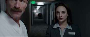 Movie still from “Sully” (2016), directed by Clint Eastwood – A woman in a suit and tie in a hallway; Medium shot, Over the shoulder angle