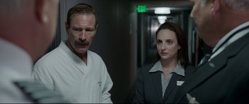 Movie still from “Sully” (2016), directed by Clint Eastwood – A man and a woman standing next to each other in a hallway; Close Up shot, Over the shoulder angle