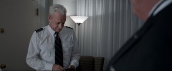 Movie still from “Sully” (2016), directed by Clint Eastwood – An older man in a white shirt and black tie; Medium shot, Low angle