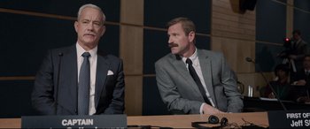 Movie still from “Sully” (2016), directed by Clint Eastwood – Two men sitting at a table wearing suits and ties; Medium shot, Over the shoulder angle