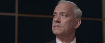 Movie still from “Sully” (2016), directed by Clint Eastwood – An older man in a suit and tie looking upward; Close Up shot, Low angle