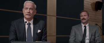 Movie still from “Sully” (2016), directed by Clint Eastwood – Two men in business suits sitting at a table in front of a wall; Medium shot, Over the shoulder angle