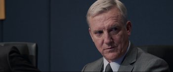 Movie still from “Sully” (2016), directed by Clint Eastwood – An older man wearing a suit and tie; Close Up shot, Over the shoulder angle