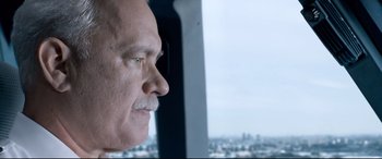 Movie still from “Sully” (2016), directed by Clint Eastwood – A man with a mustache looking out of a window; Close Up shot, Over the shoulder angle