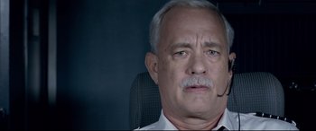 Movie still from “Sully” (2016), directed by Clint Eastwood – An older man with a mustache is looking at the camera; Close Up shot, Low angle