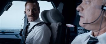 Movie still from “Sully” (2016), directed by Clint Eastwood – A man sitting in the back seat of a vehicle; Close Up shot, Low angle