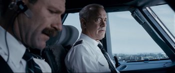 Movie still from “Sully” (2016), directed by Clint Eastwood – An older man in a uniform sitting in a vehicle; Close Up shot, Over the shoulder angle