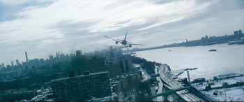 Movie still from “Sully” (2016), directed by Clint Eastwood – An airplane is flying low over a large city; Extreme Wide shot, Low angle