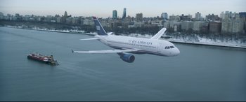 Movie still from “Sully” (2016), directed by Clint Eastwood – An airplane flying over a body of water with a city in the background; Extreme Wide shot, High angle