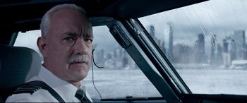 Movie still from “Sully” (2016), directed by Clint Eastwood – An older man with a mustache and a tie in a car; Close Up shot, Low angle